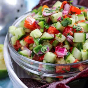 a bowl of cucumber de gallo next to blue corn chips