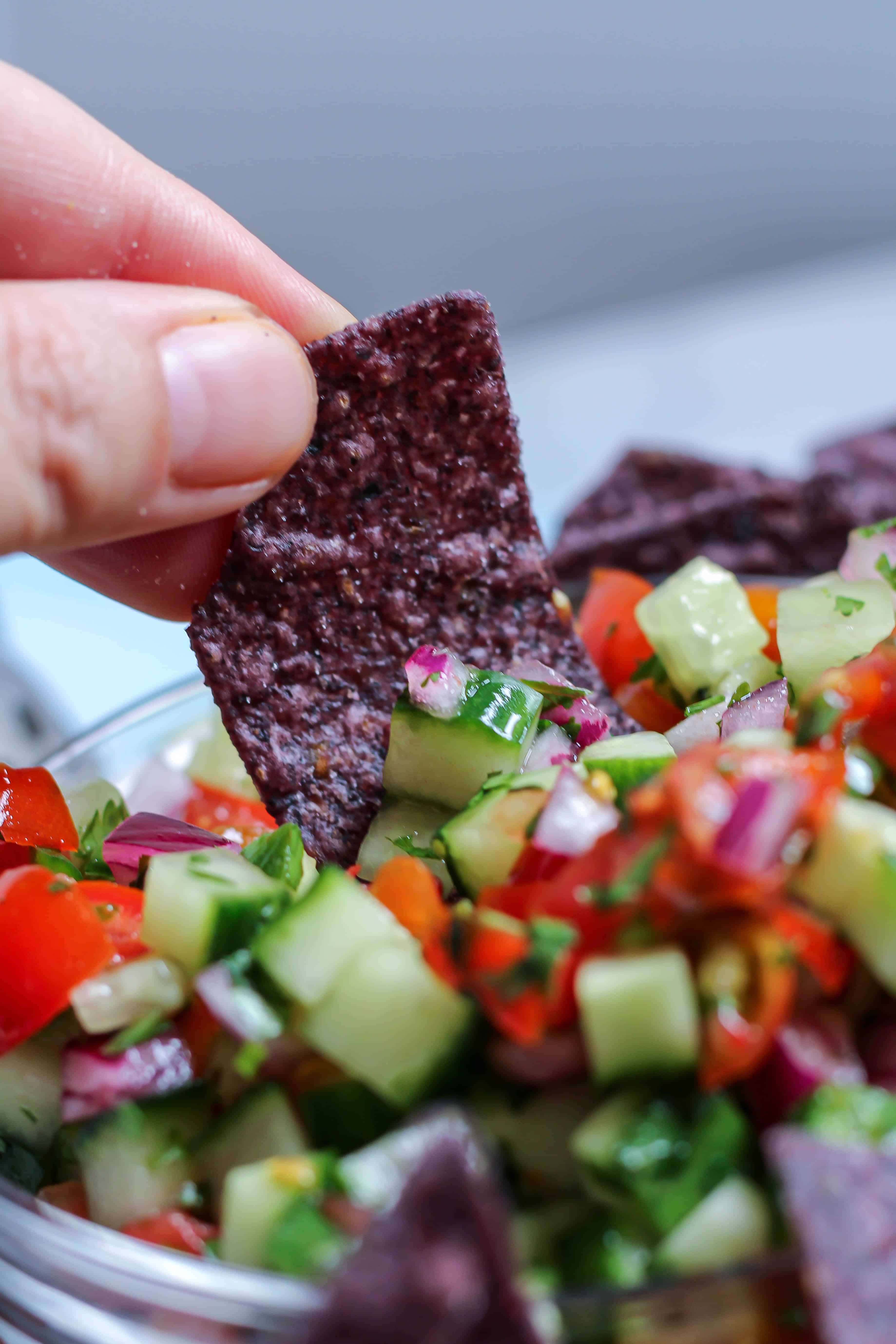 dipping a chip into cucumber pico de gallo