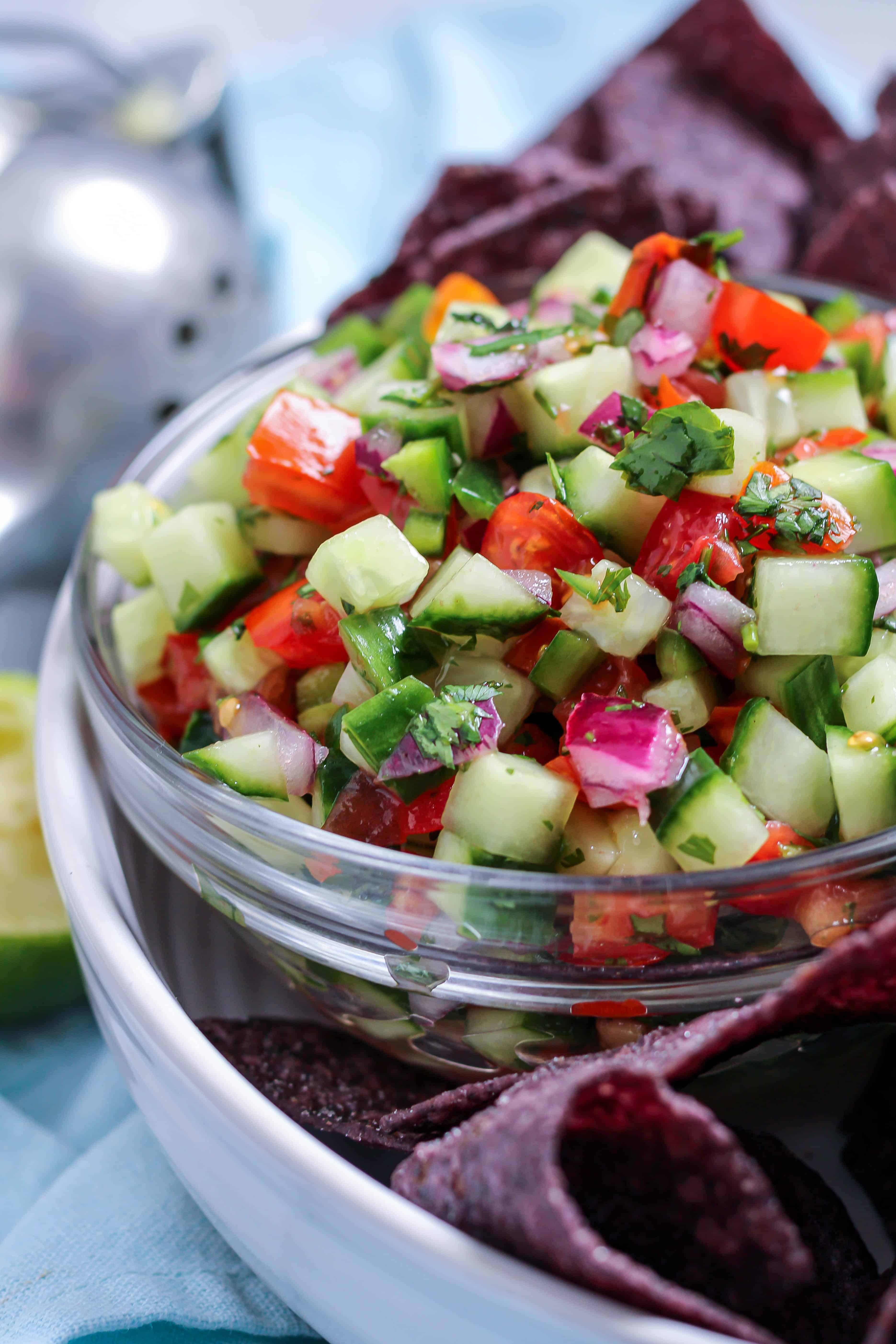 a bowl of cucumber de gallo next to blue corn chips