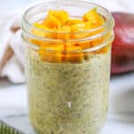 a jar of mango overnight oats topped with fresh mango and lime zest