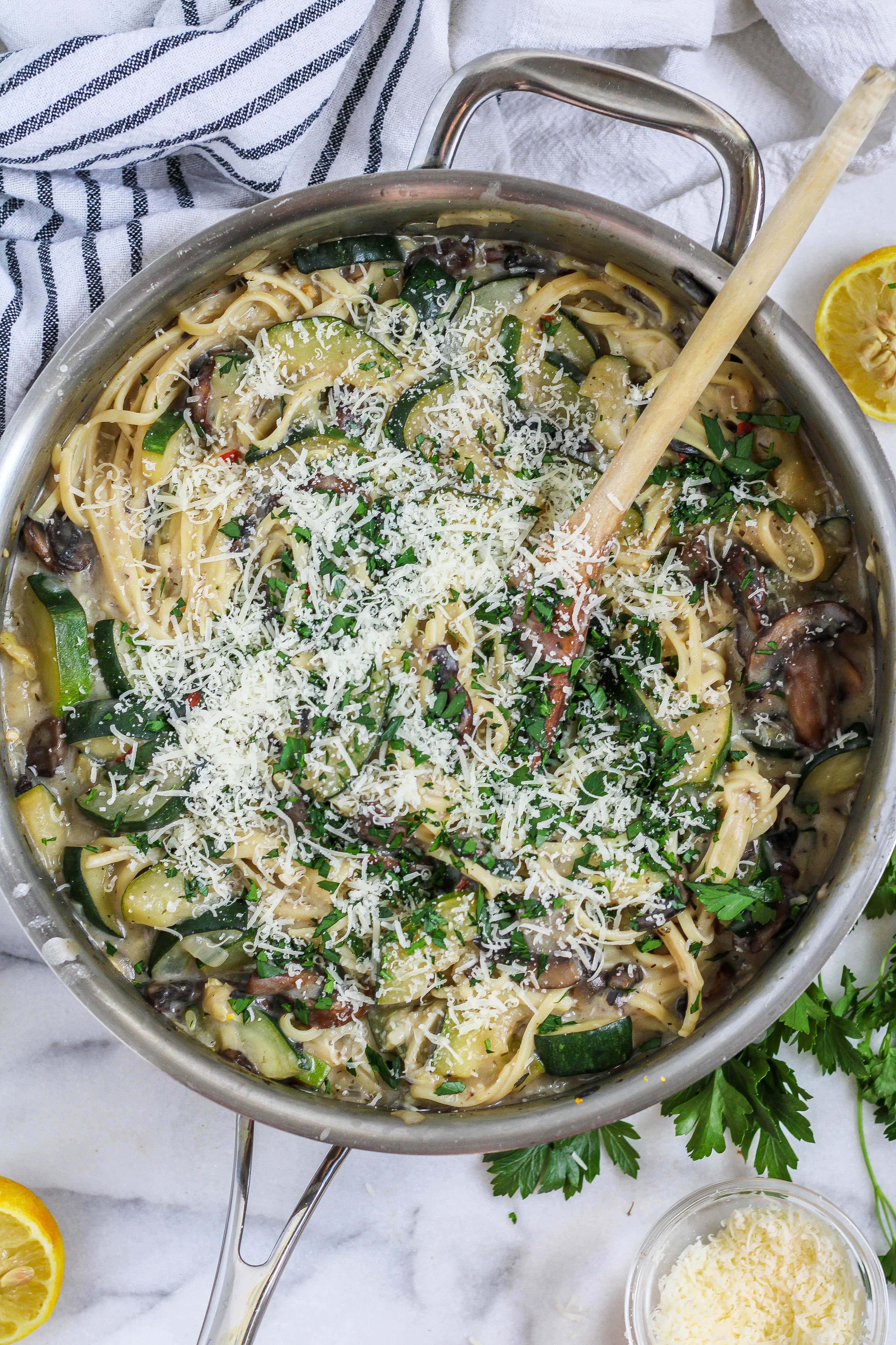 a large pan of creamy mushroom zucchini pasta garnished with parmesan and parsley