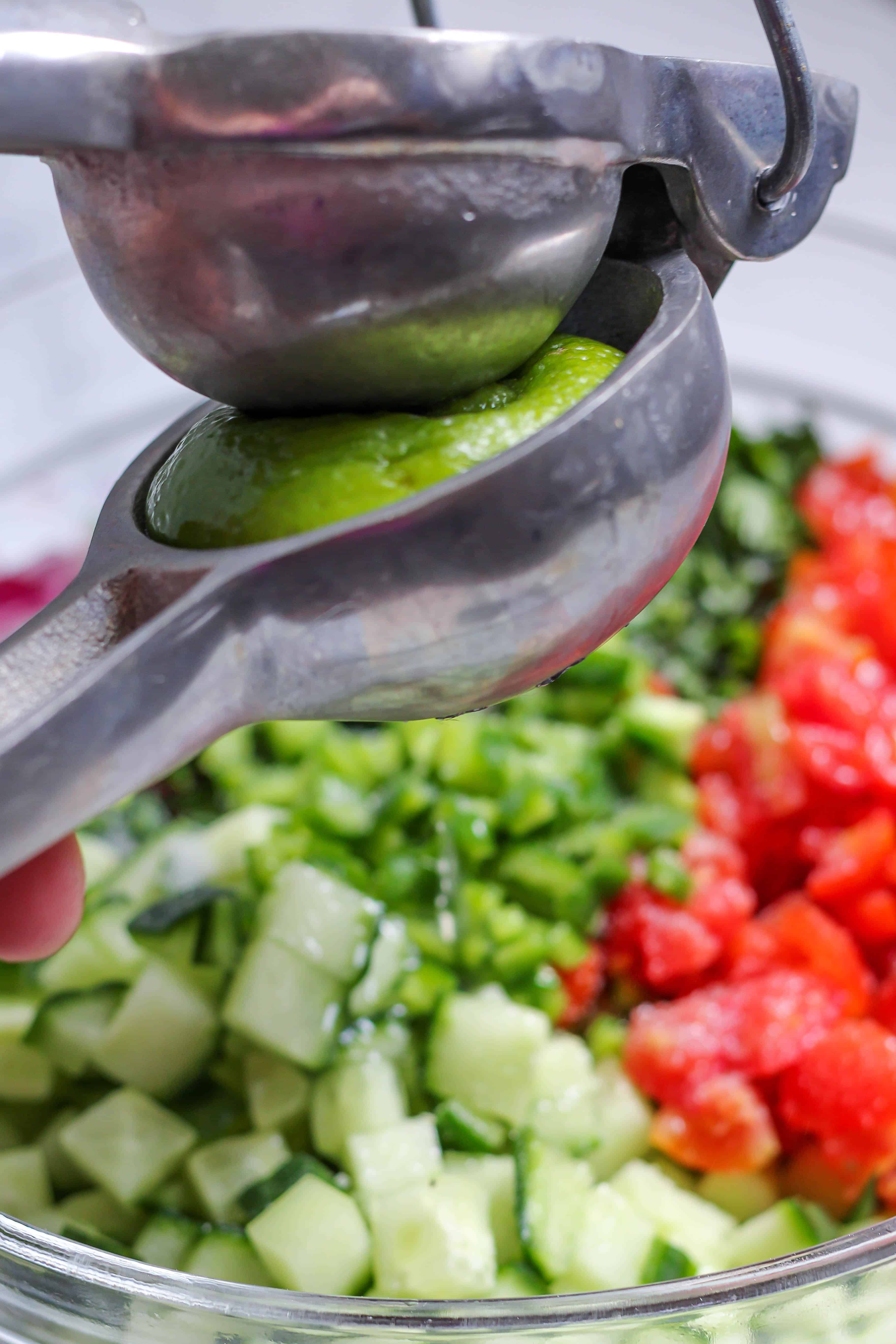 squeezing lime over cucumber pico de gallo salsa