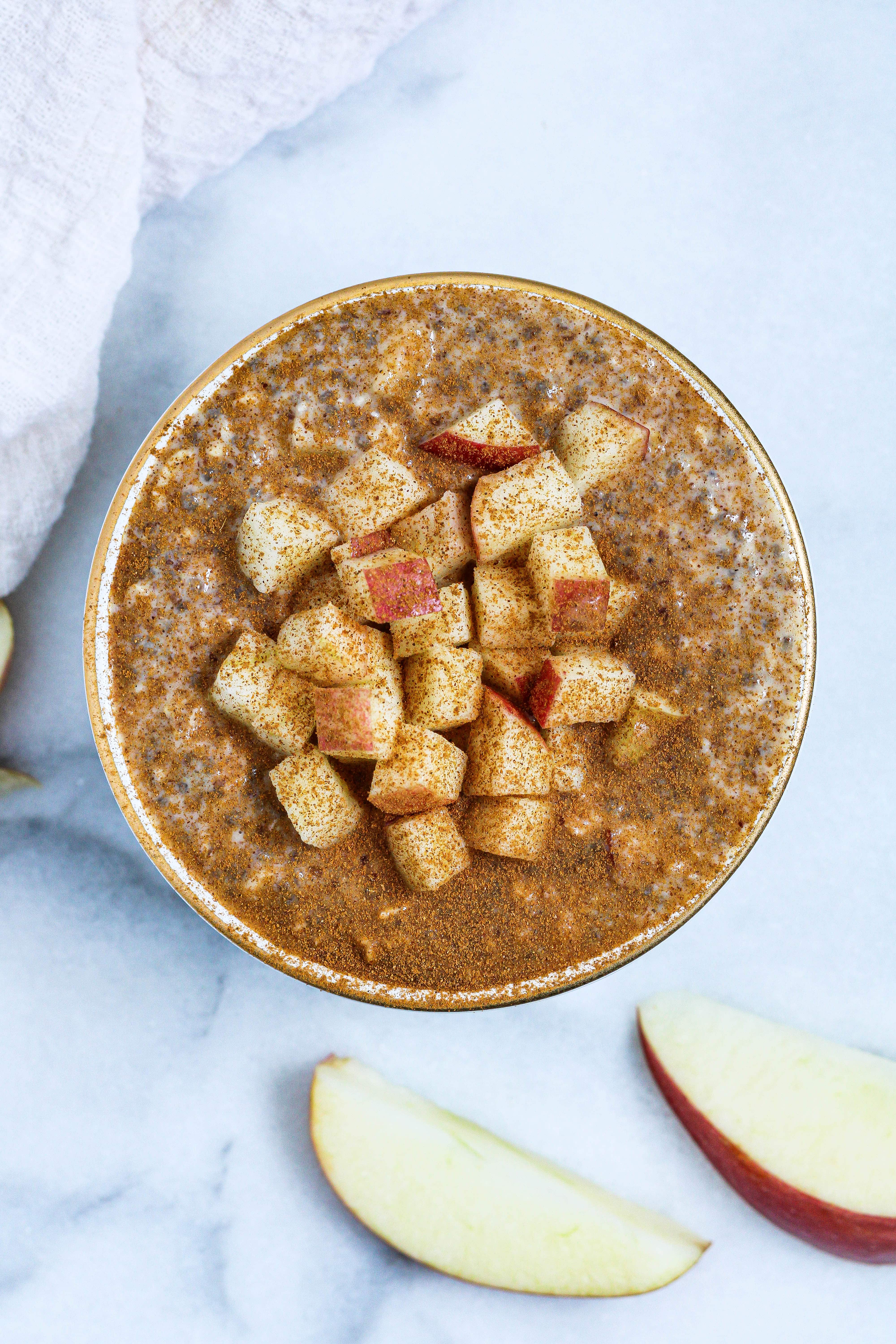 Apple Pie Overnight Oats dusted with cinnamon in a white and gold bowl