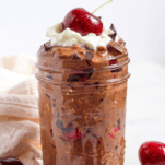 a jar of black forest overnight oats with a cherry on top