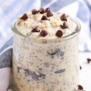 blue and white kitchen towel behind a small glass jar of chocolate chip cookie dough overnight oats