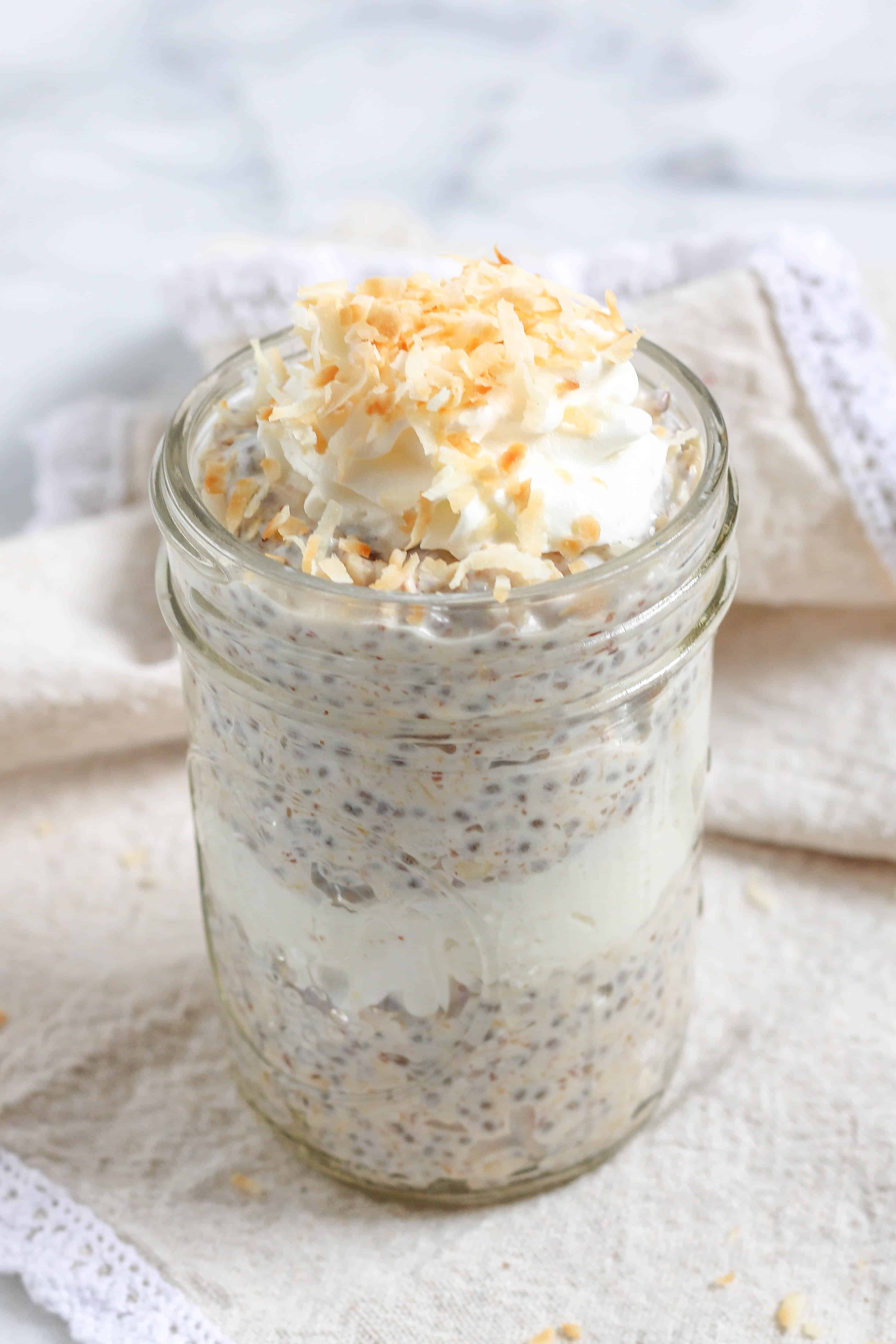 A jar of coconut cream pie overnight oats layered with whipped cream