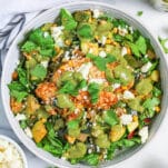 a bowl of poblano corn salad with chicken topped with avocado dressing, queso fresco, and cilantro