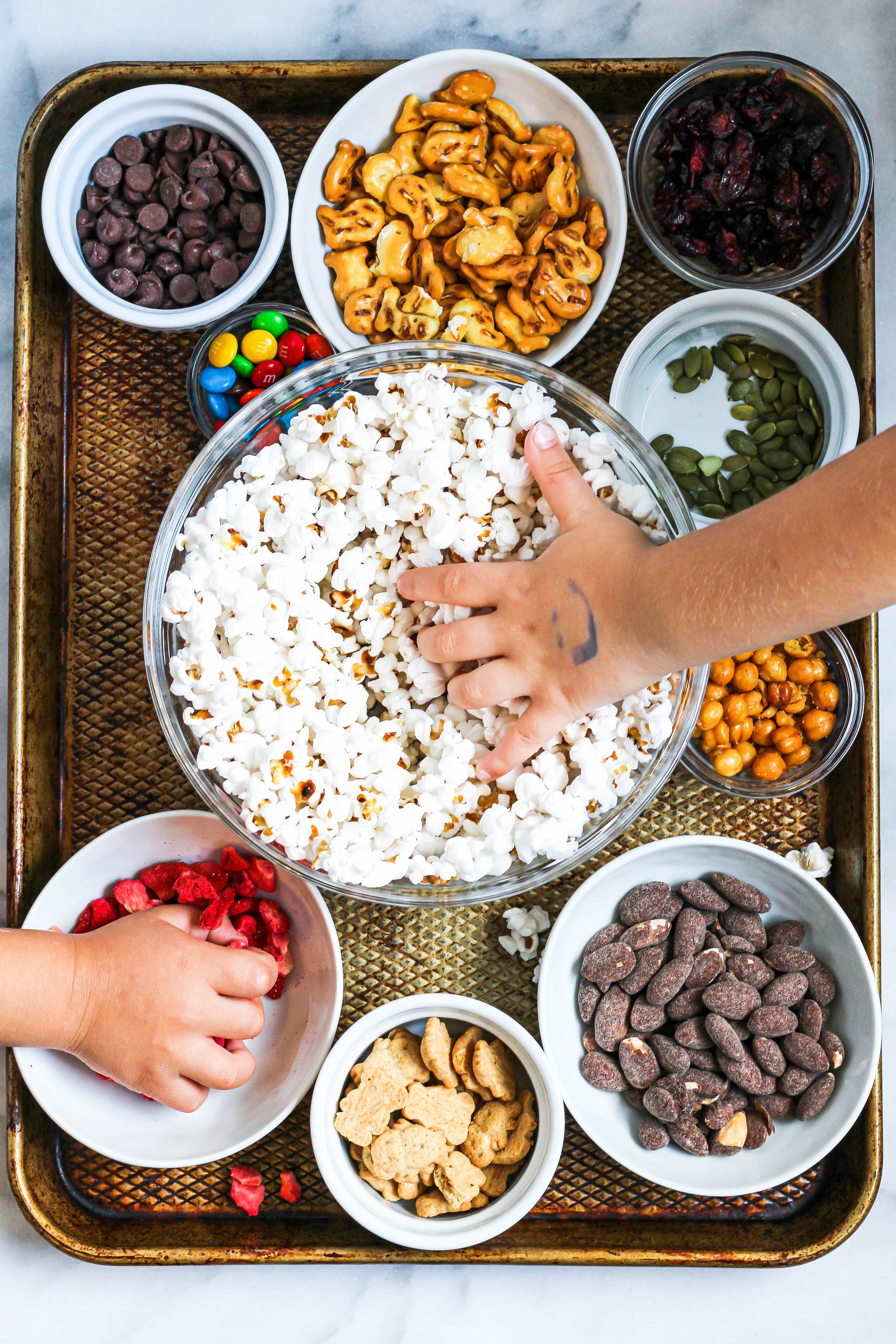 little kid hands making their own popcorn trail mix