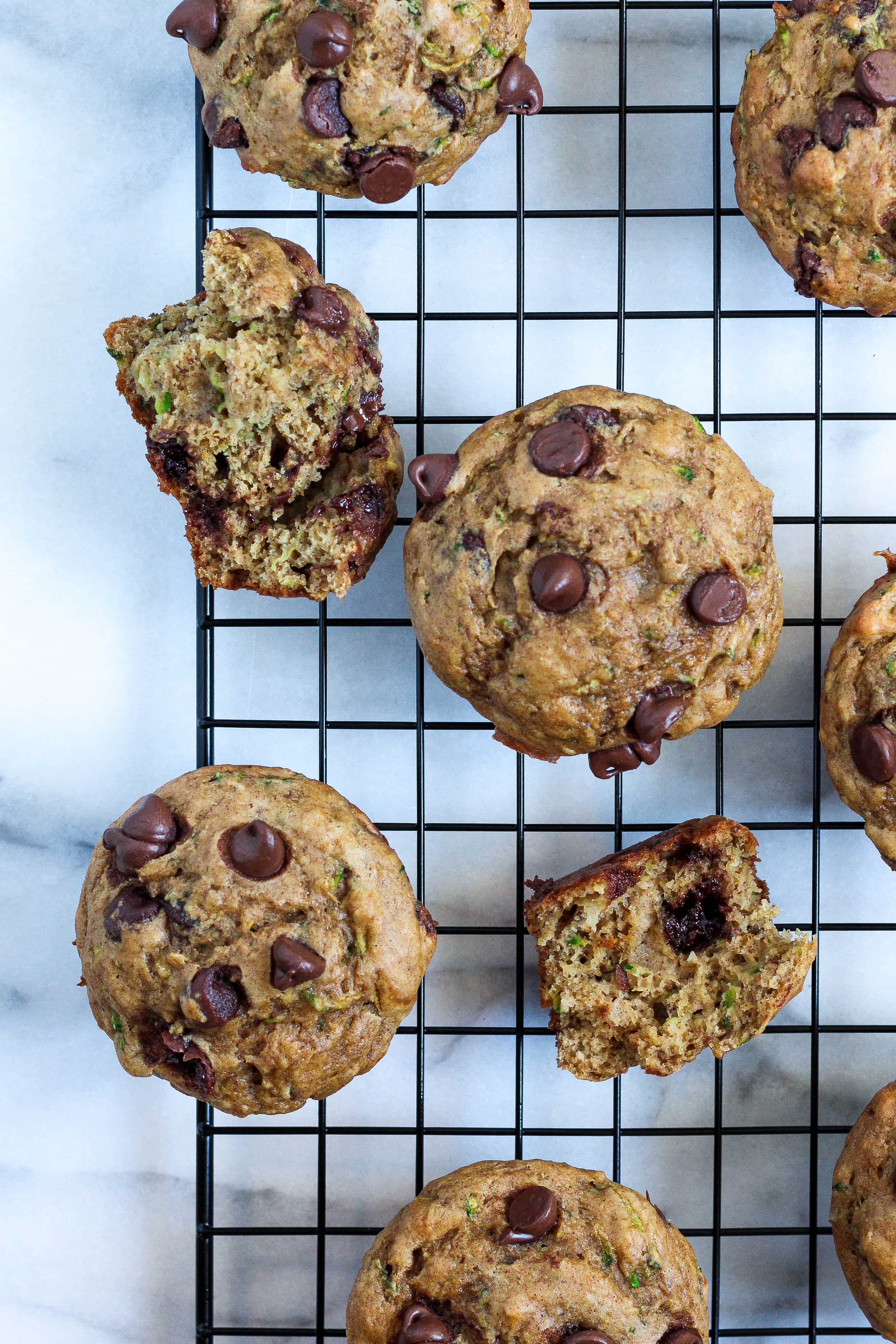 zucchini banana chocolate chips muffins on a black cooling rack over marble