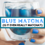hands with blue nails holding a glass cup of blue tea with text overlay that says, "Blue Matcha (is it even really matcha!?)"