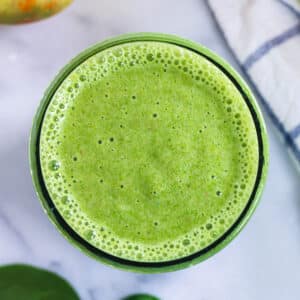 overhead look at a glass of green spinach banana apple smoothie