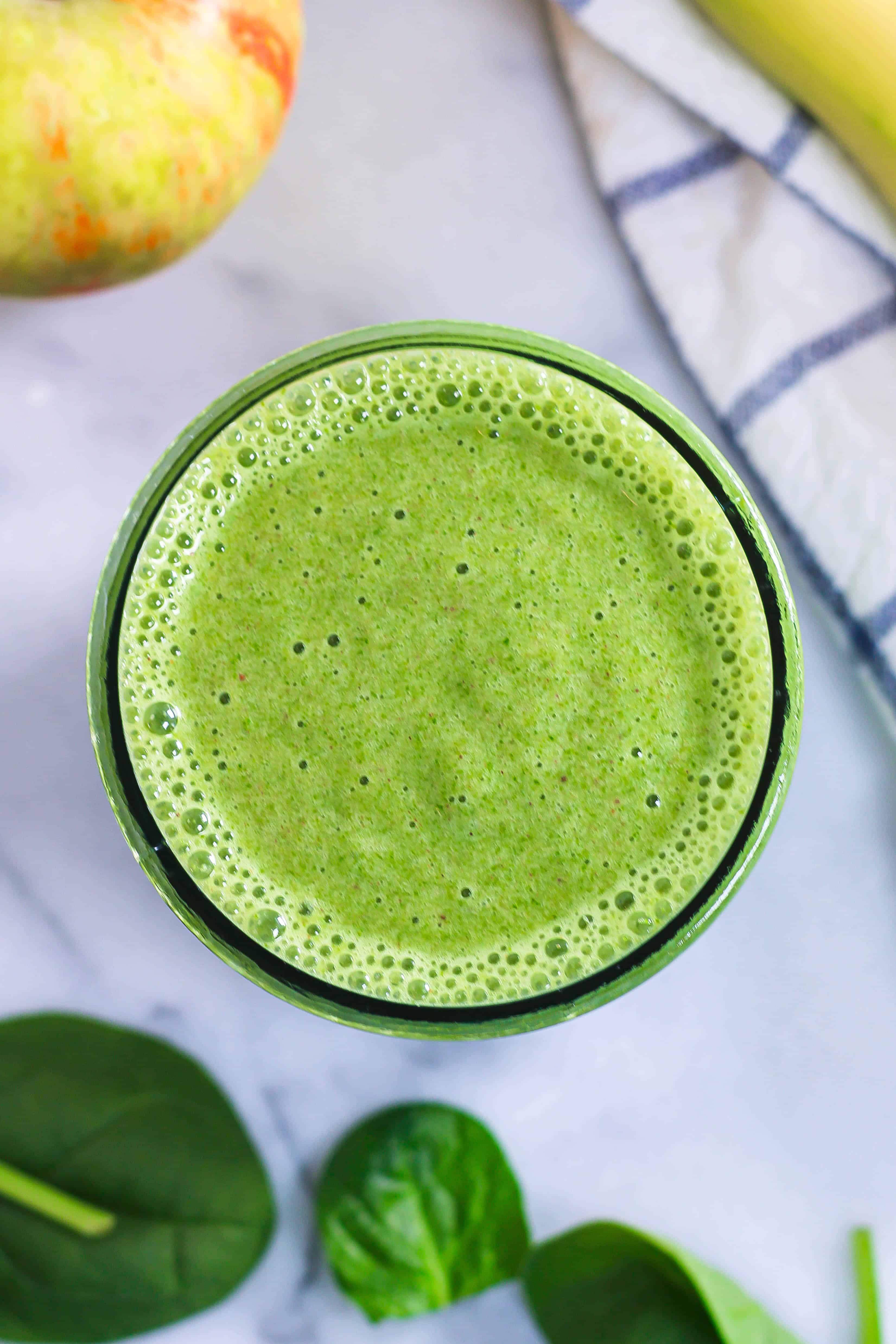 overhead look at a glass of green spinach banana apple smoothie