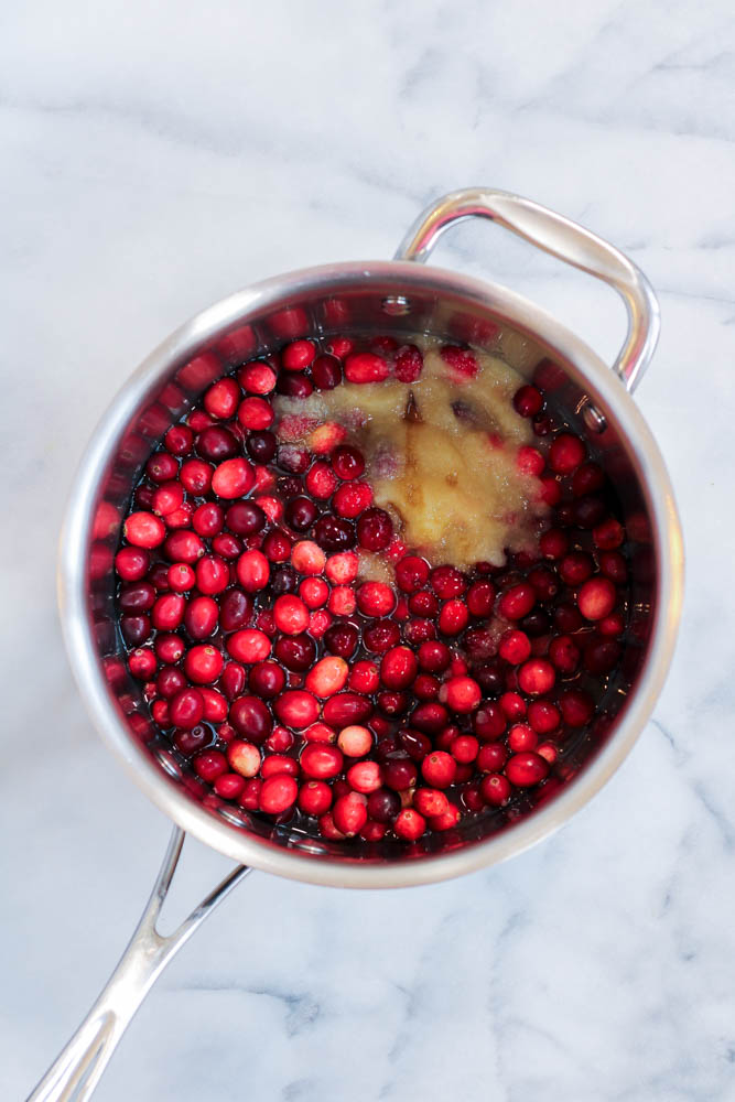 ingredients in a saucepan to make apple cider cranberry sauce