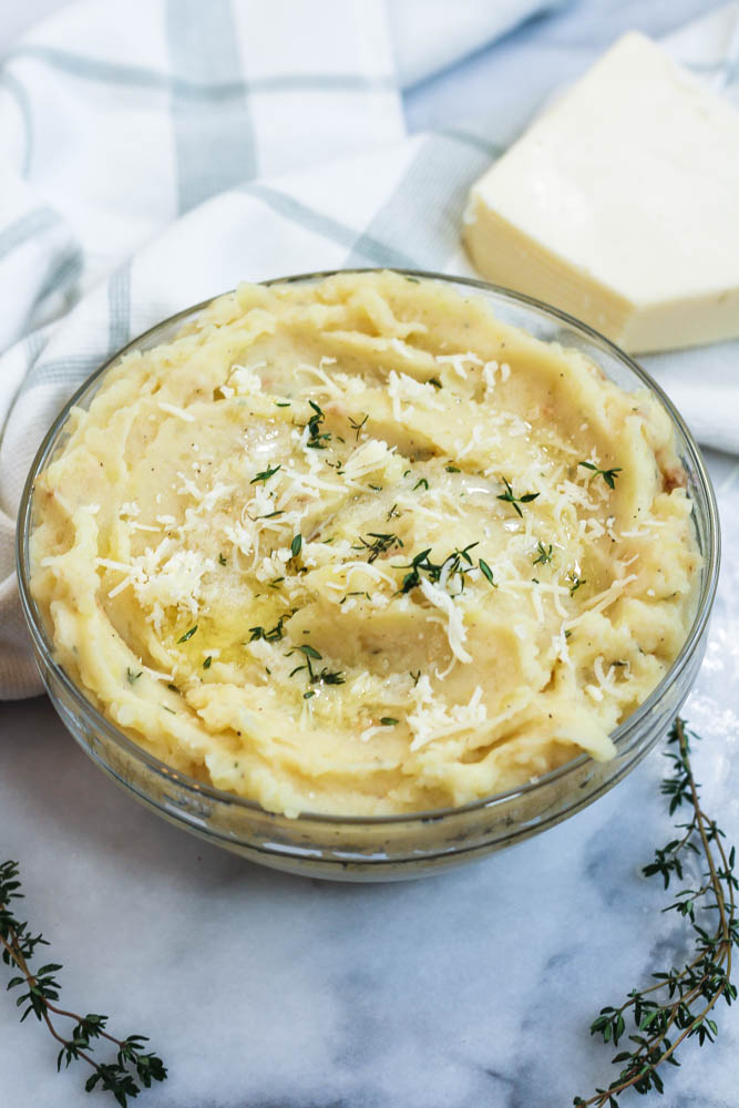 thyme and asiago atop a glass bowl of asiago mashed potatoes
