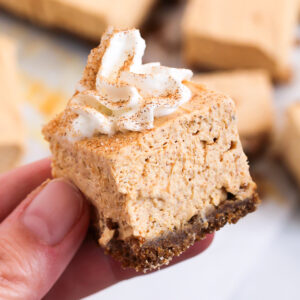 rich and creamy no bake pumpkin cheesecake bars with a gingersnap crust and whipped topping garnished with cinnamon sugar