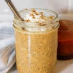 a jar of pumpkin protein overnight oats with a dollop of whipped cream on top