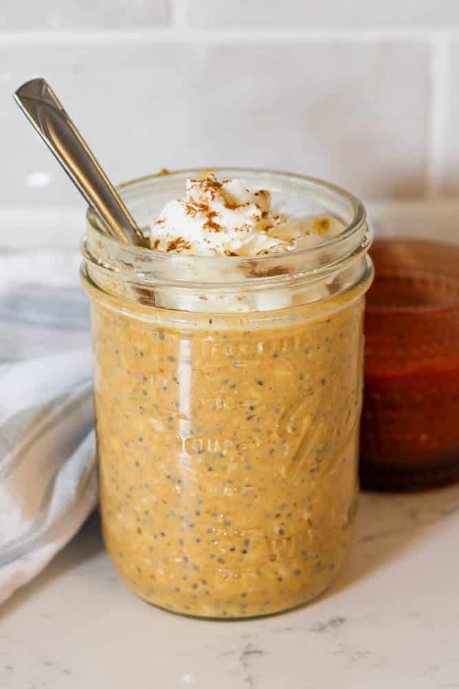 a jar of pumpkin protein overnight oats with a dollop of whipped cream on top