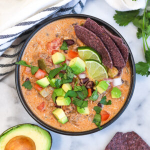 a bowl of creamy beef taco soup with lots of garnishes