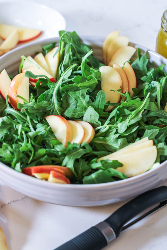 groups of crisp apple slices nestled into a bed of arugula for a simple apple manchego salad