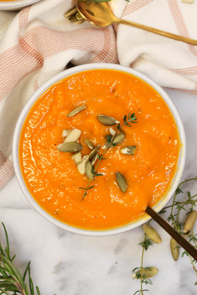 overhead picture of a bowl of roasted carrot and butternut squash soup on a marble surface