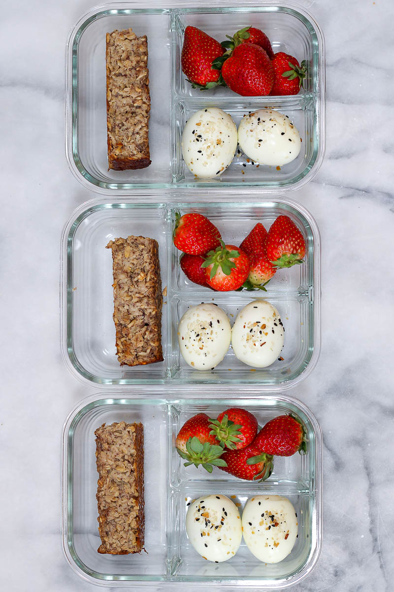 meal prep breakfast bento box with banana bread baked oatmeal, hard boiled eggs, and strawberries