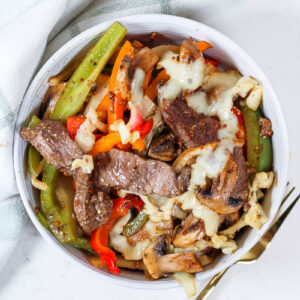 Philly Cheesesteak Bowls by a green kitchen towel and golden fork