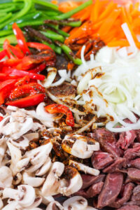 ingredients on a sheet pan to make philly cheesesteak bowls