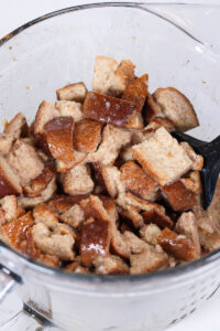 mixing bread pieces into the egg mixture for french toast muffin cups