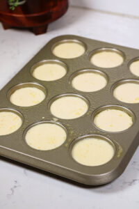 pouring the egg mixture into a prepared muffin pan to make spinach feta egg bites