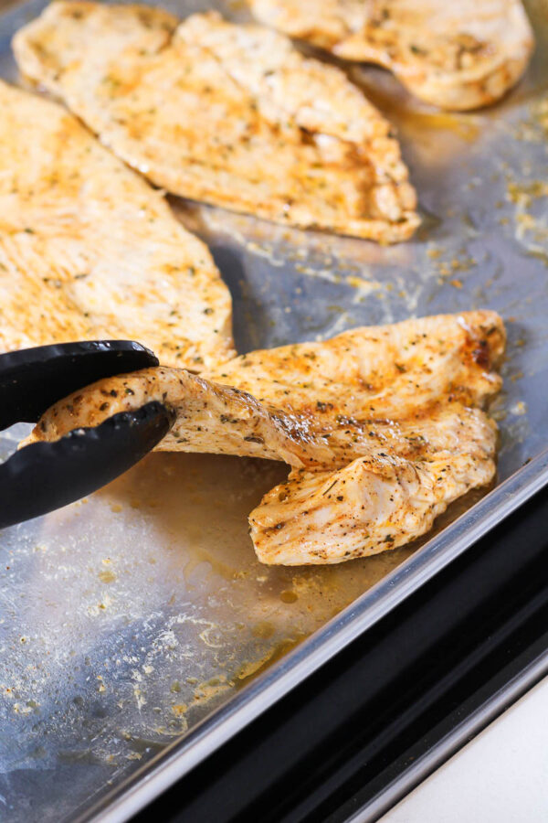 flipping the oven baked thin sliced chicken halfway through cooking time
