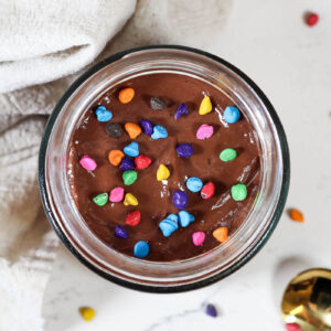 cosmic brownie overnight oats with rainbow chip sprinkles in a glass jar