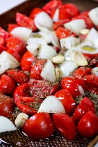 tomatoes, garlic, and onion on a sheet pan to make roasted tomato pasta sauce