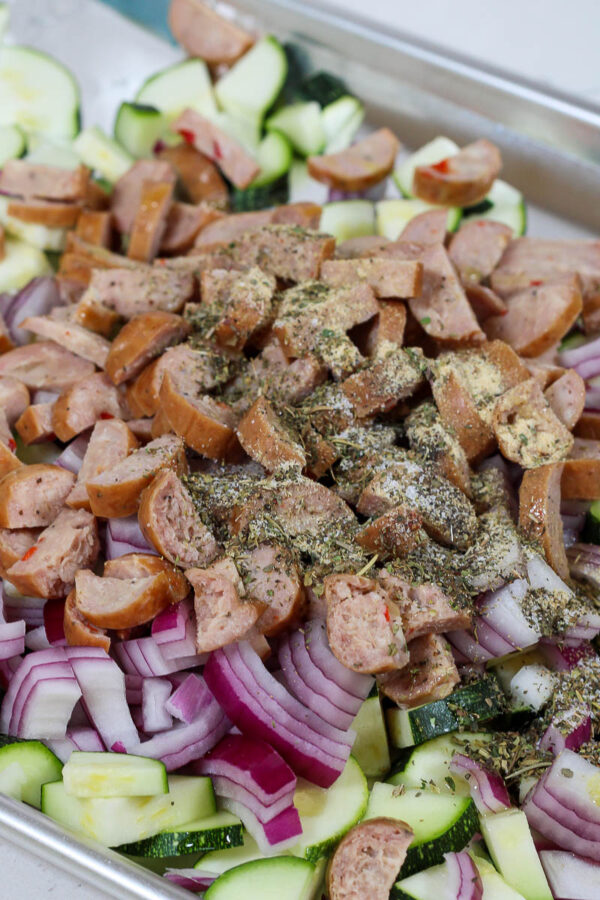 making zucchini pasta salad with all ingredients tossed on a sheet pan
