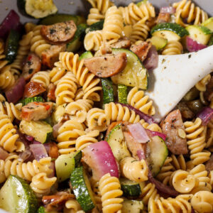 stirring zucchini pasta salad
