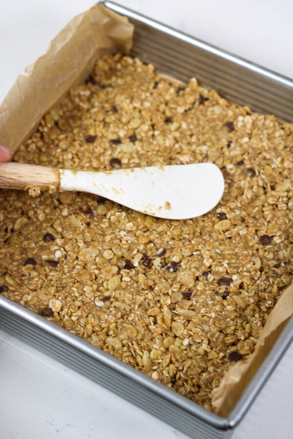 pressing granola mixture into a pan for nut free granola bars