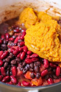 adding pumpkin and beans to pumpkin chili with turkey