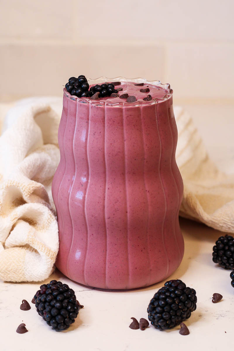 a chocolate blackberry smoothie in a curvy glass