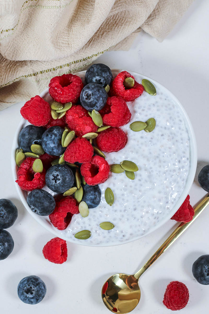 greek yogurt chia pudding topped with blueberries, raspberries, and pumpkin seeds