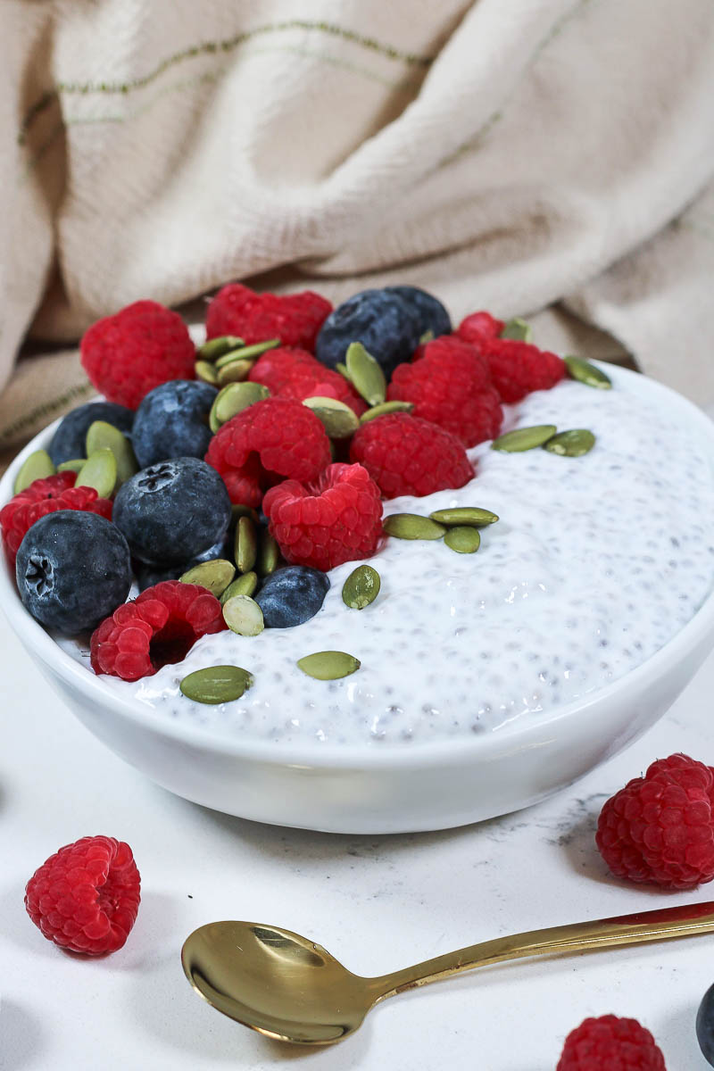 a bowl of yogurt chia pudding with berries and pumpkin seeds