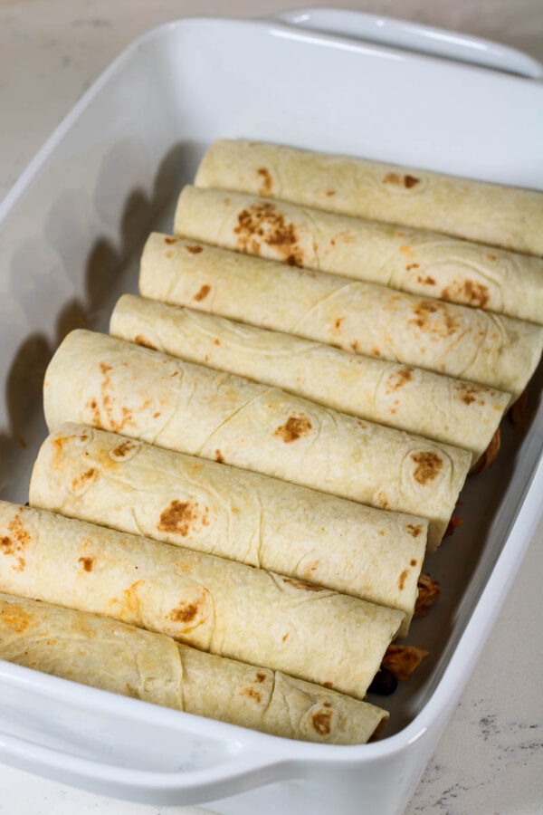 rolled enchiladas placed seam-side down in baking pan