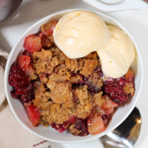 apple blackberry crumble in a bowl with vanilla ice cream