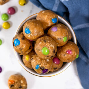 monster cookie protein balls with dye free candies in a white and gold bowl