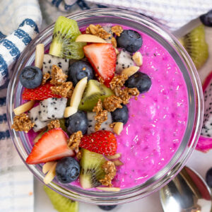 vibrant pink purple pitaya bowl topped with fresh fruit and granola